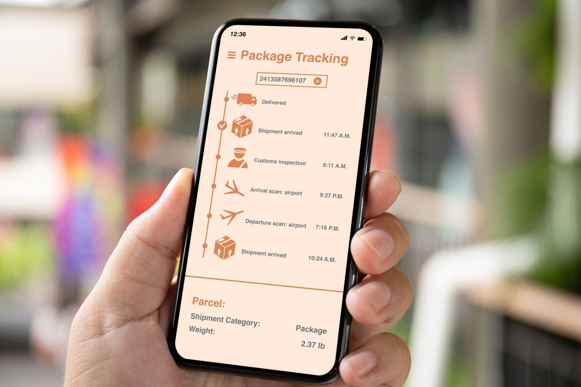 man hand holding phone with app tracking delivery package on the screen background of a city street